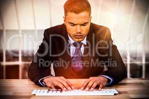 Composite image of businessman typing on keyboard at desk