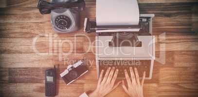 Businesswoman typing on typewriter by vintage camera and phone