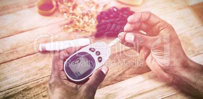Cropped hands testing blood sugar with glucometer
