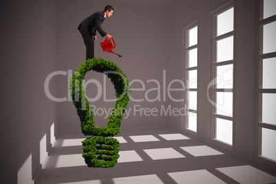 Composite image of businessman watering with red can