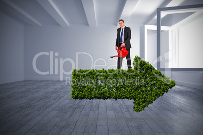 Composite image of businessman holding red watering can