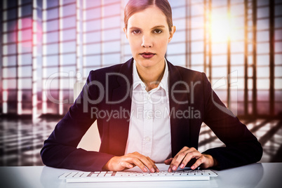 Composite image of portrait of businesswoman typing on keyboard at desk