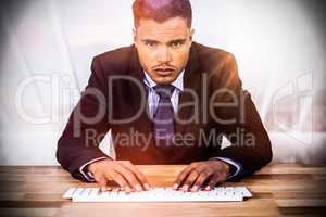 Composite image of portrait of businessman typing on keyboard at desk