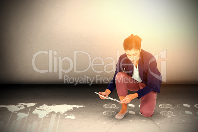 Composite image of businesswoman kneeling while using digital tablet