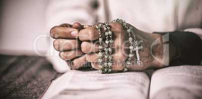 Woman hands praying with rosary and bible