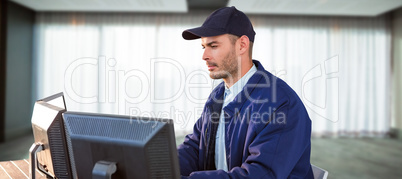 Composite image of serious security officer using computer