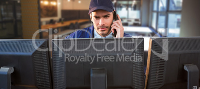 Composite image of security officer talking on phone while using computer at desk