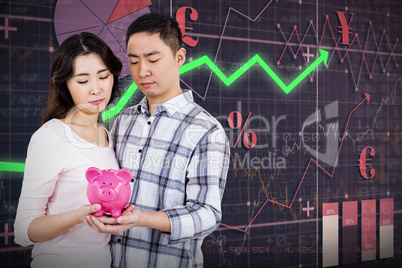 Composite image of couple holding their piggy bank