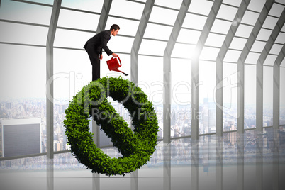 Composite image of businessman watering with red can