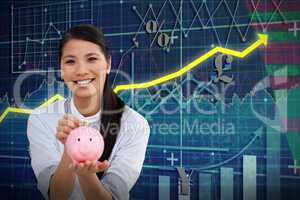 Composite image of charming businesswoman saving money in a piggybank