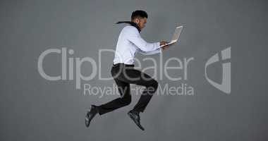 Composite image of businessman using laptop while jumping