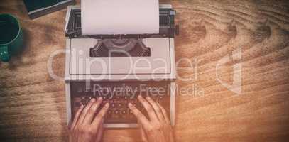 Hands of businesswoman typing on typewriter by vintage camera and coffee cup