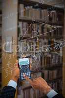 Composite image of cropped hands of businessman using calculator