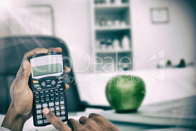 Composite image of hands of businessman using calculator