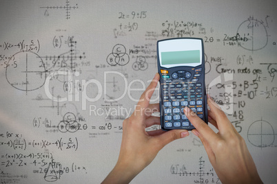 Composite image of cropped hands of businesswoman using calculator