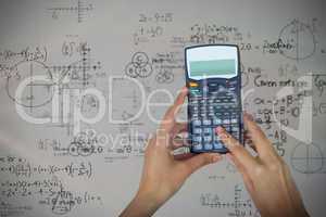 Composite image of cropped hands of businesswoman using calculator