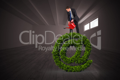 Composite image of businessman holding red watering can