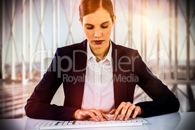 Composite image of businesswoman typing on keyboard at desk
