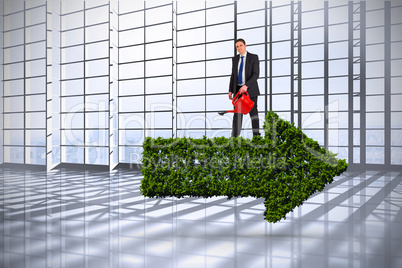 Composite image of businessman holding red watering can