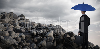 Composite image of rear view of businessman holding blue umbrella and briefcase