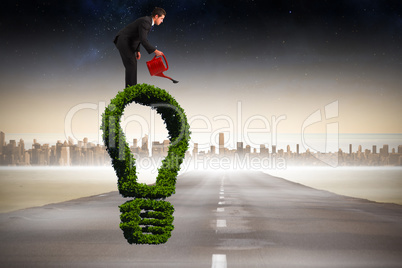 Composite image of businessman watering with red can