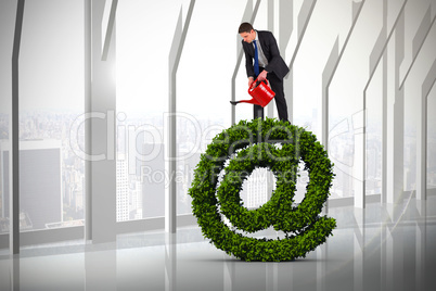 Composite image of businessman holding red watering can