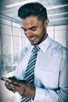 Composite image of smiling businessman using mobile phone