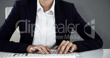 Composite image of portrait of smiling businesswoman typing on keyboard at desk