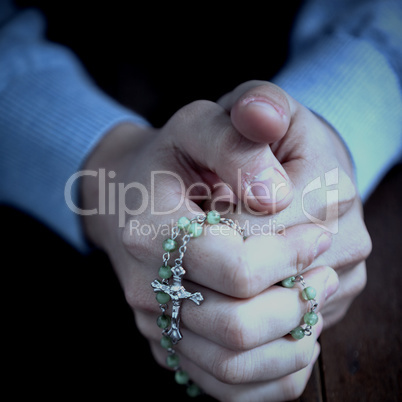 Praying hands of man with rosary