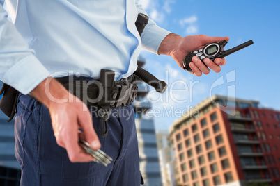 Composite image of mid section of security officer holding hand cuff and walkie talkie