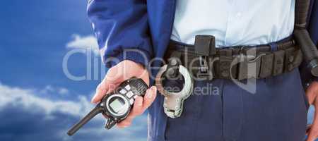 Composite image of mid section of security officer holding walkie talkie