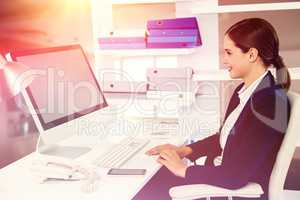 Composite image of smiling businesswoman working on computer