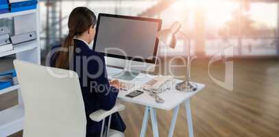 Composite image of rear view of businesswoman using computer