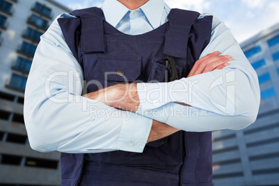 Composite image of mid section of security officer standing with arms crossed