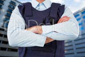 Composite image of mid section of security officer standing with arms crossed