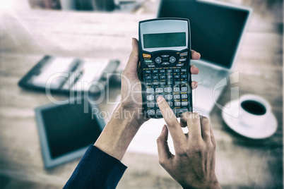 Composite image of hands of businesswoman using calculator