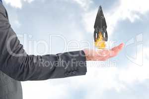 Businessman holding a rocket taking off from his hand against sky background