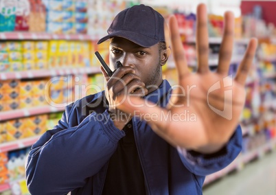 security guard of the supermarket saying stop with his hand (blurred) and speaking with the walkie-t