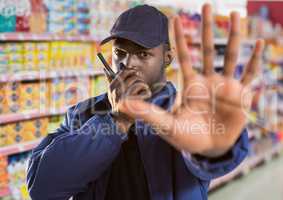 security guard of the supermarket saying stop with his hand (blurred) and speaking with the walkie-t