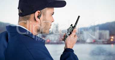 Security guard with cap and walkie talkie against blurry skyline