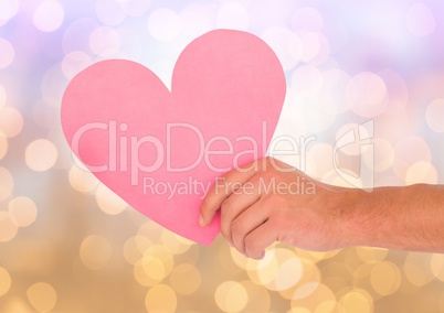 Hand holding cut out heart with sparkling light bokeh background