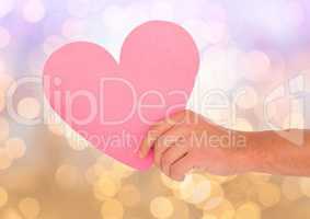 Hand holding cut out heart with sparkling light bokeh background