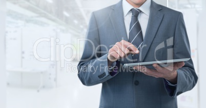Businessman holding tablet in bright long room space