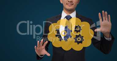 Business man with yellow cloud and gear graphic between hands against dark blue background