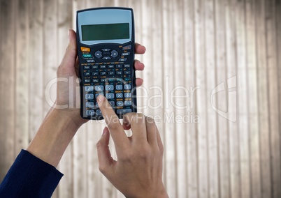 Hands with calculator against blurry wood panel