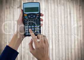 Hands with calculator against blurry wood panel