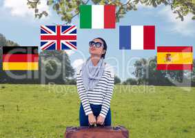 main language flags around young woman with suitcase in field
