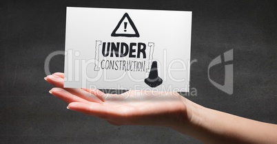 Hand with card showing grey construction doodle against grey wall