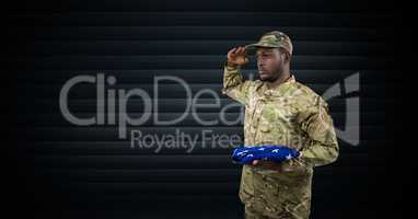 soldier saluting with the USA flag in his hand. dark background