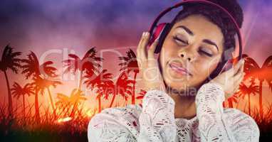 Happy casual woman listenning music with headphones in front of plam trees background